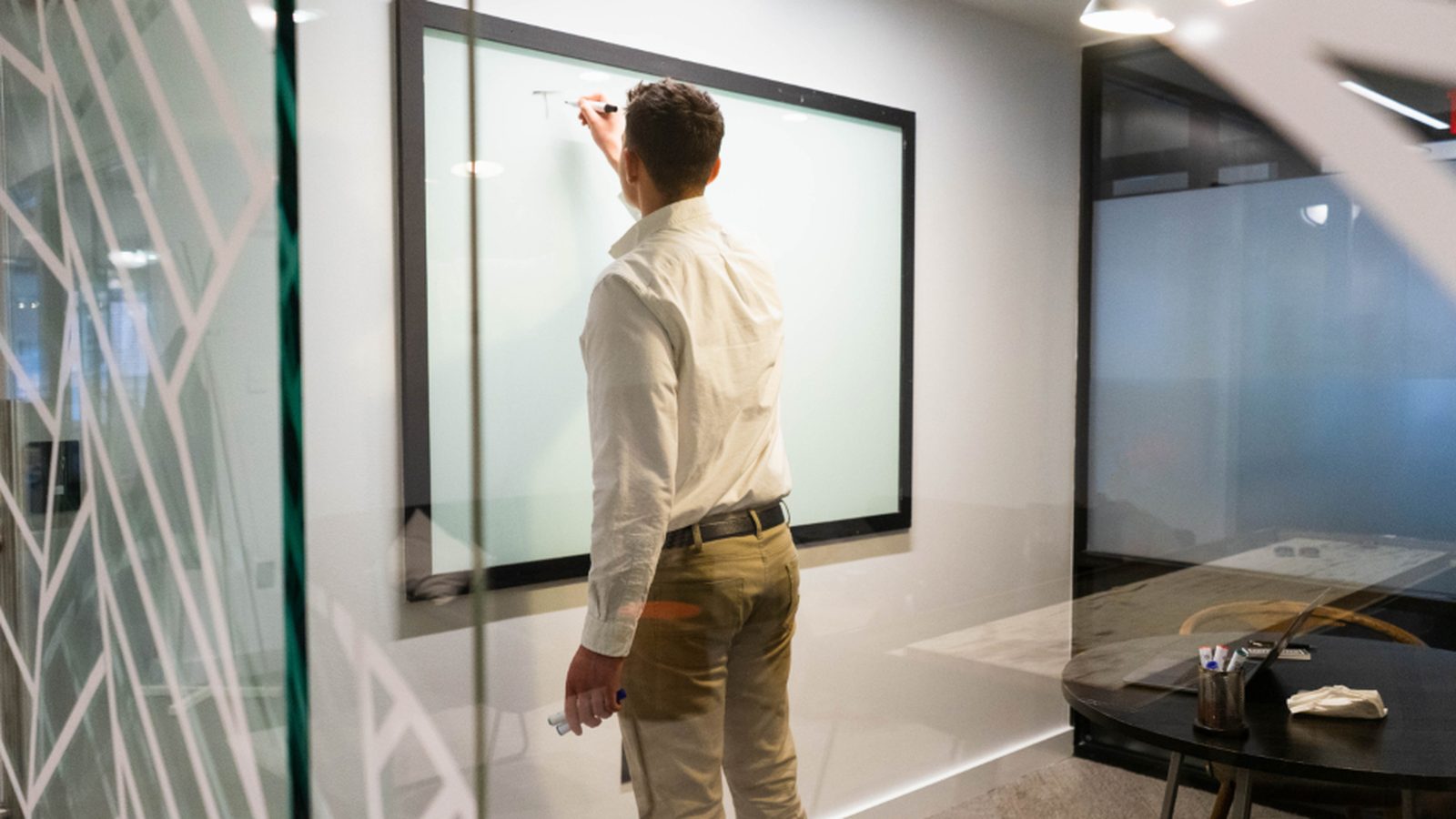A consultant working through a plan at a whiteboard with a team